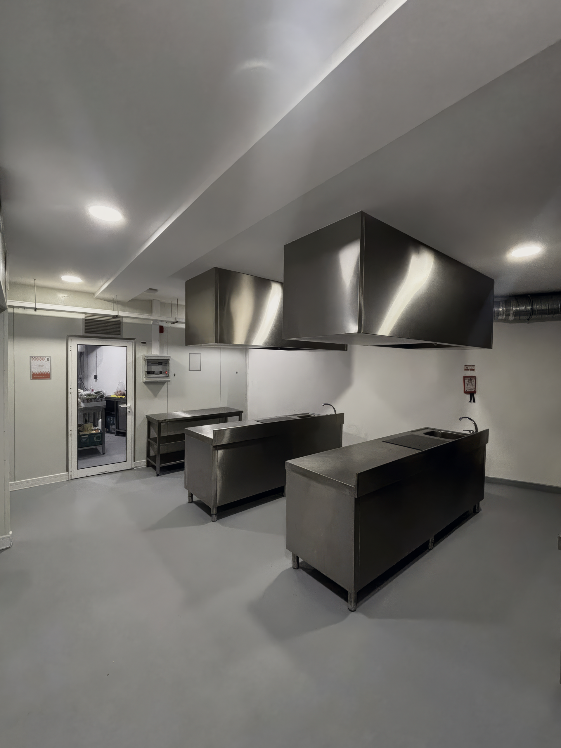 Cozinha industrial moderna com bancadas em aço inoxidável e grandes hottes de extração