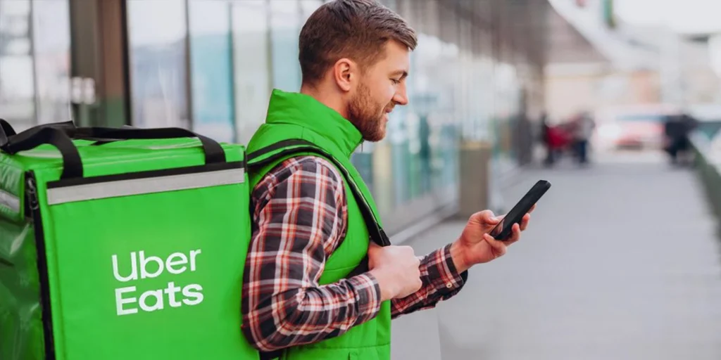 Estafeta com uma mochila da Uber Eats a consultar o telemóvel